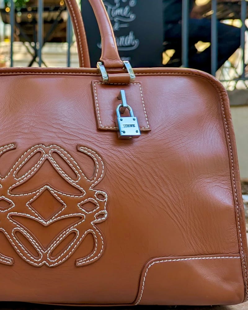 Detail of the tan Loewe Amazona: a rolled leather handle, the silver padlock and the stitched anagram